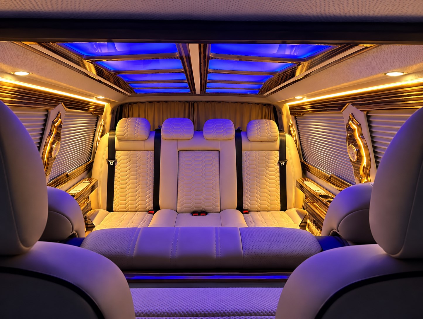 Cream leather rear seating with blue and gold ambient lighting inside a VIP van.